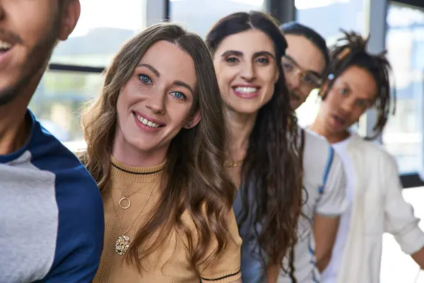 Retrato de alegre liderança da equipe feminina olhando para a câmera perto de colegas multiétnicos no escritório moderno — Fotografia de Stock