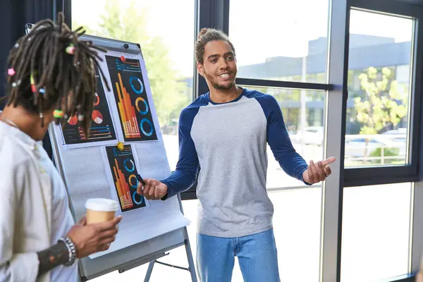 Stylish african american manager talking near flip and colleague with coffee to go in office — Stock Photo