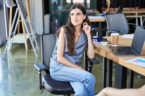 Pensativa mulher de negócios em trajes casuais sentado e olhando para longe perto de laptop e café para ir — Fotografia de Stock