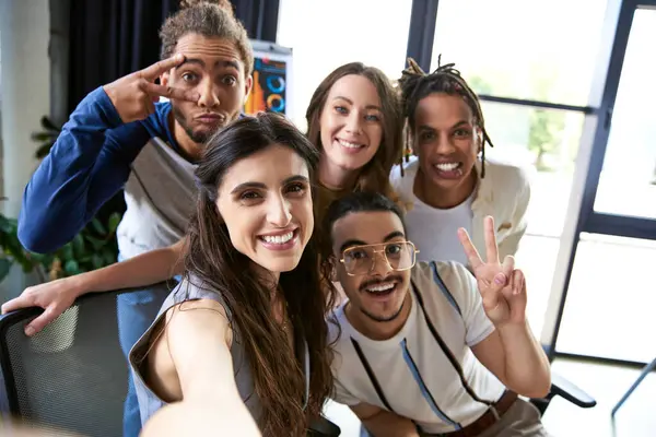 Retrato de alegre equipo multiétnico haciendo gestos y mirando a la cámara en la moderna oficina de coworking - foto de stock