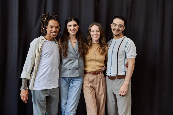Group photo of smiling multicultural employees looking at camera on black backdrop in office — Stock Photo