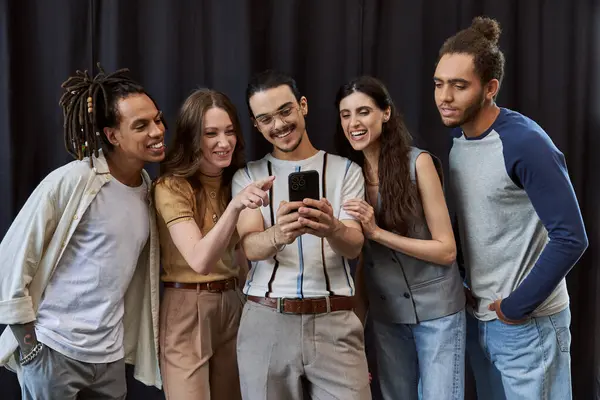 Cheerful manager using smartphone near multicultural team on black backdrop in office, group photo — Stock Photo