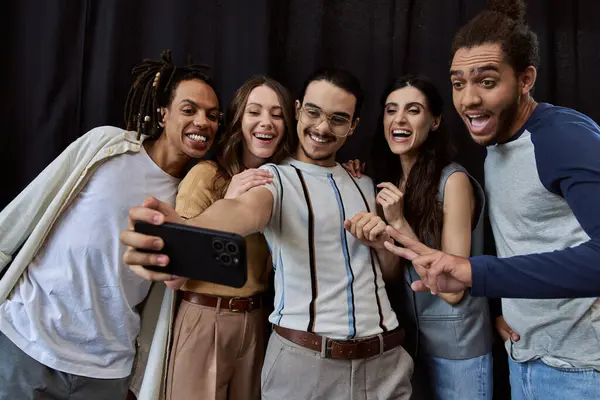 Excité homme dans les lunettes de prendre selfie sur téléphone mobile avec équipe créative interracial au bureau — Photo de stock