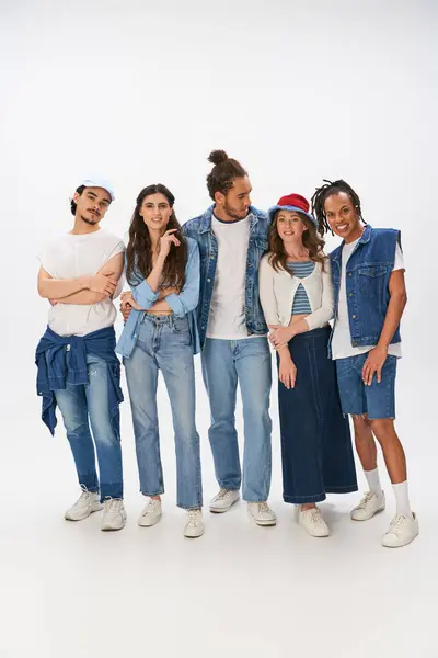 Полная длина межрасовых друзей в модных нарядах и джинсовой одежде, стоящих на сером фоне — стоковое фото