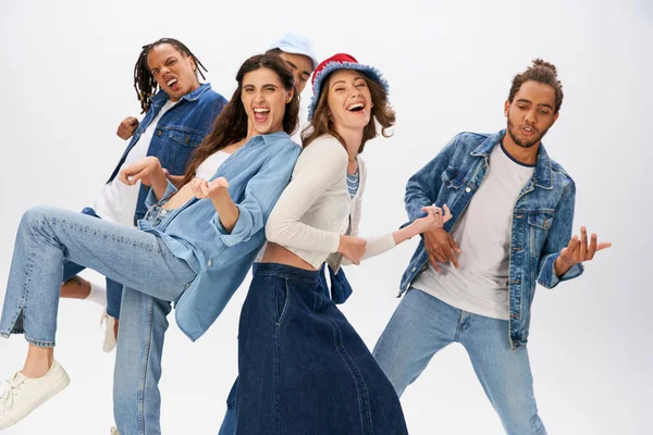 Cheerful multiethnic friends in stylish casual wear having fun and dancing on grey backdrop — Stock Photo