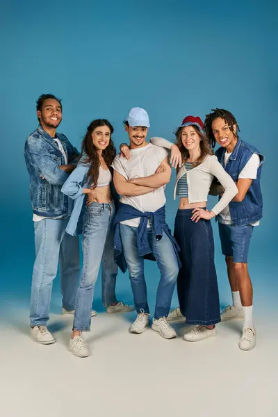 Full length of interracial friends in trendy and denim clothes on blue backdrop, grip portrait — Stock Photo