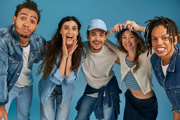 Overjoyed multicultural friends in stylish street wear having fun and looking at camera on blue — Stock Photo