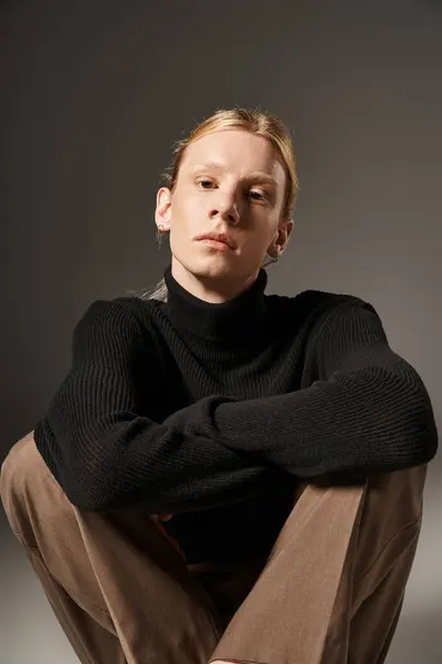 Vertical shot of young non binary person sitting on floor with crossed legs and looking at camera — Stock Photo