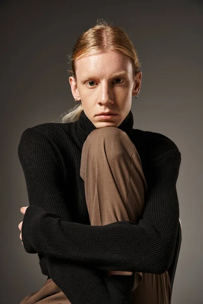 Young attractive non binary person with ponytail and black turtleneck posing and looking at camera — Stock Photo