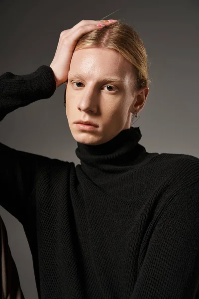 Vertical shot of attractive non binary person with red hair and ponytail posing with hand on face — Stock Photo