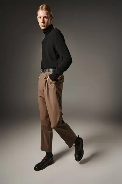 Вертикальный снимок молодой небинарной модели в черной водолазке с руками в карманах, мода — стоковое фото