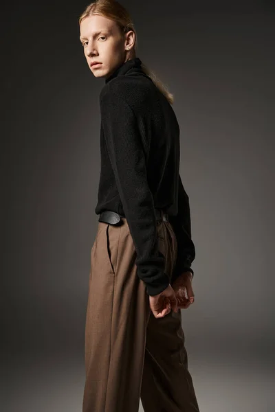 Handsome non binary model with red hair and ponytail posing with hands behind back, fashion concept — Stock Photo