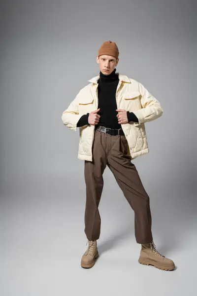 Vertical shot of young non binary person in warm winter jacket and beanie hat looking at camera — Stock Photo