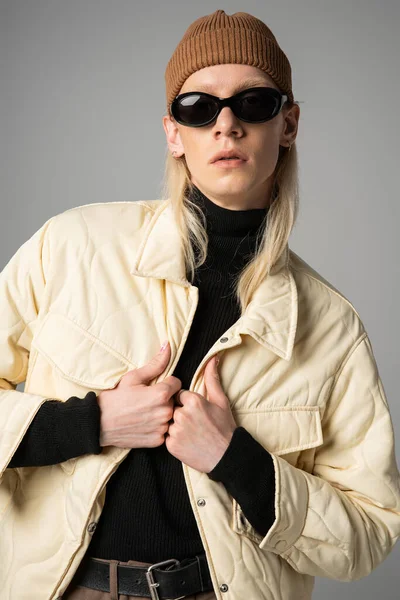 Attraente persona non binaria in elegante abbigliamento invernale posa su sfondo grigio, concetto di moda — Foto stock