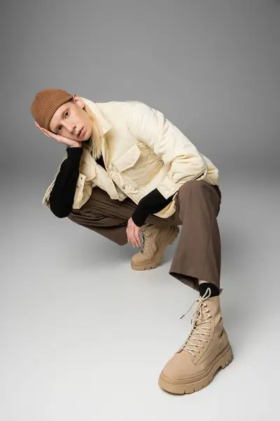 Vertical shot of appealing androgynous model with trendy beanie hat in warm jacket looking at camera — Stock Photo