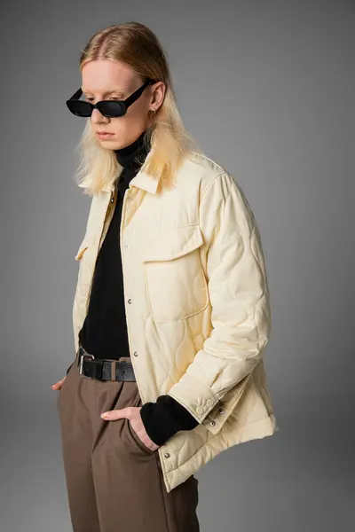 Tiro vertical de pelo largo modelo no binario en traje de invierno con gafas de sol mirando hacia abajo, la moda - foto de stock