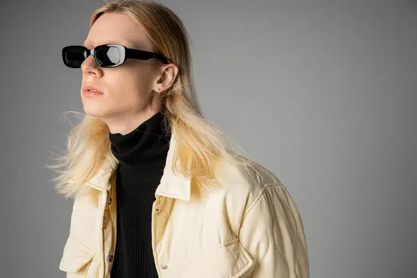 Gut aussehende junge nichtbinäre Person in Winterjacke mit Sonnenbrille, die wegschaut, Mode — Stockfoto