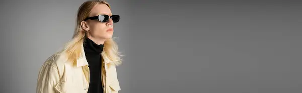 Pessoa andrógina elegante na jaqueta de inverno com óculos de sol olhando para longe, conceito de moda, bandeira — Fotografia de Stock