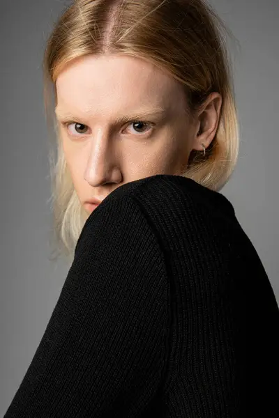 Vertical shot of appealing non binary model in black turtleneck with long hair looking at camera — Stock Photo
