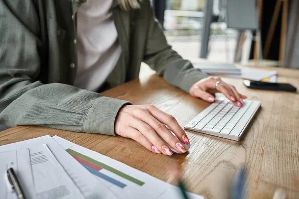 Vue recadrée des mains avec vernis à ongles de personne androgyne travaillant à table au bureau, entreprise — Photo de stock