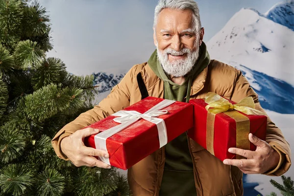Гарний вигляд Санта з білою бородою в теплій куртці тримає подарунки і весело посміхається, зима — стокове фото