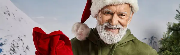 Bel cappello di Babbo Natale con borsa regalo rossa sorridente alla macchina fotografica, concetto invernale, banner — Foto stock