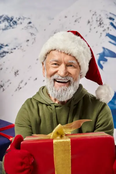 Portrait of bearded Santa holding big red present wearing red hat and mittens, Christmas concept — Stock Photo