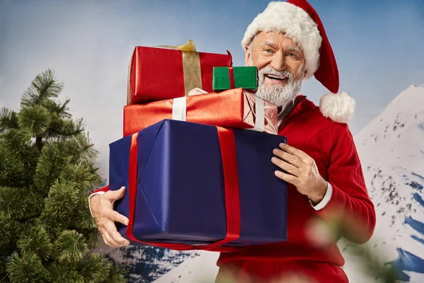 Fröhlicher Weihnachtsmann mit riesigen Stapeln von Geschenken und fröhlichem Lächeln in die Kamera, winterliches Konzept — Stockfoto