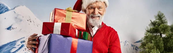 Fröhlicher Mann im Weihnachtsmannkostüm mit weißem Bart, der Geschenke vor der Kamera zeigt, Winterkonzept, Banner — Stockfoto