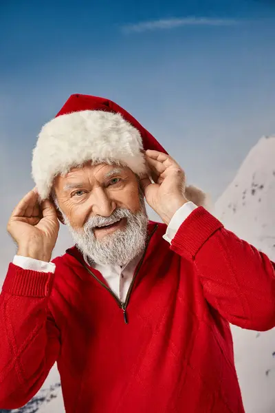 Alegre Papai Noel barbudo branco com as mãos em seu chapéu de Natal olhando para câmera, conceito de inverno — Fotografia de Stock