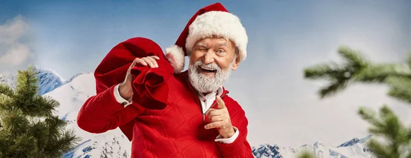 Verspielter Mann im Weihnachtsmannkostüm zwinkert und zeigt mit dem Finger in die Kamera, Frohe Weihnachten, Banner — Stockfoto