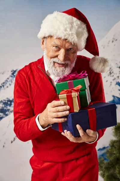 Homme barbu gai habillé en Père Noël avec chapeau de Noël tenant pile de cadeaux, concept d'hiver — Photo de stock
