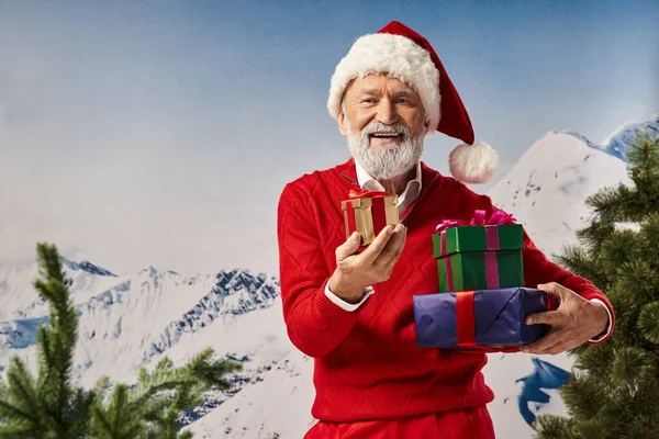 Lustige weiße bärtige Weihnachtsmänner posieren mit Geschenken vor verschneiter Bergkulisse, Winterkonzept — Stockfoto
