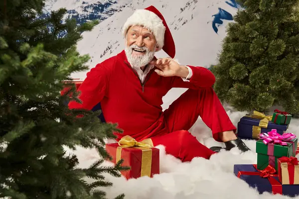 Cheerful dreamy man in Santa costume posing on snow with presents looking away, Merry Christmas — Stock Photo