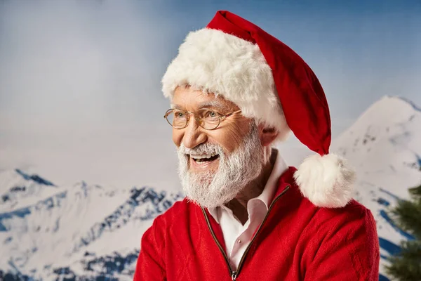 Hombre alegre en traje rojo de Santa y gafas sonriendo felizmente con telón de fondo nevado, concepto de invierno - foto de stock
