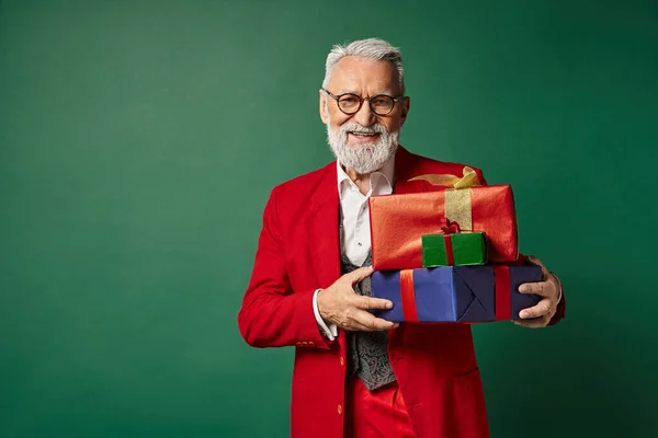 Весела Санта в окулярах позує з купою подарунків і посміхається на камеру, різдвяна концепція — стокове фото