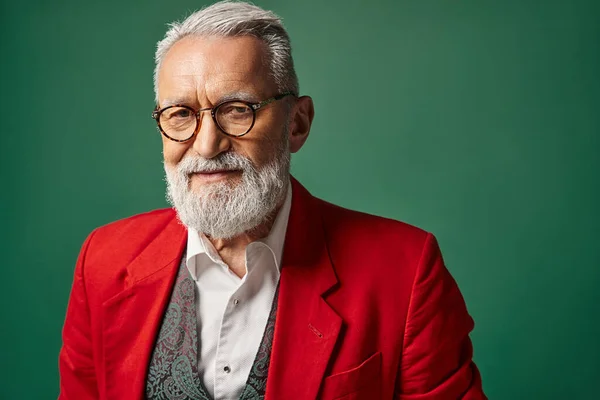 Jolly Santa Claus with beard and glasses posing on green backdrop looking at camera, winter concept — Stock Photo