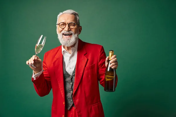 Елегантний чоловік одягнений як Санта насолоджується шампанським і весело посміхається на камеру, зимова концепція — стокове фото