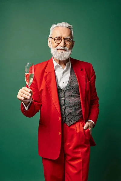 Schöner, fröhlicher Weihnachtsmann posiert mit einem Glas Champagner mit der Hand in der Tasche, Winterkonzept — Stockfoto