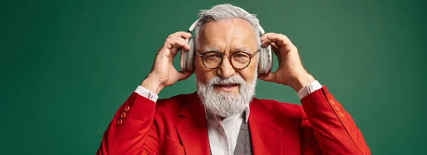 Élégant Père Noël avec barbe et lunettes portant des écouteurs regardant caméra, hiver, bannière — Photo de stock
