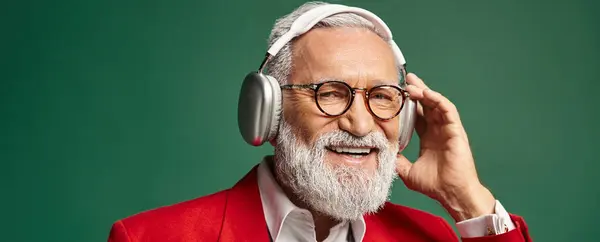 Cheerful man dressed as Santa Claus with beard and headphones smiling at camera, winter, banner — Stock Photo