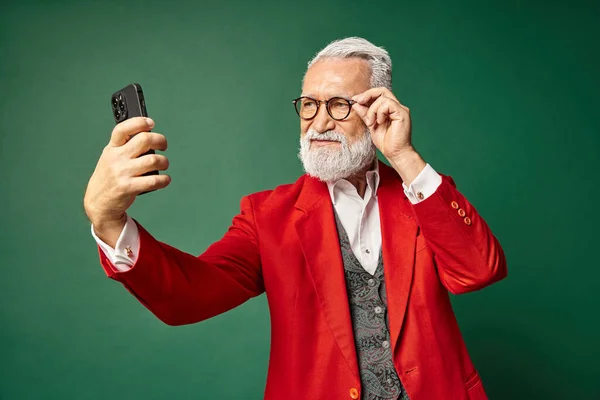 Стильный красивый мужчина одетый как элегантный Санта делает серьезные селфи по телефону, зимняя концепция — стоковое фото