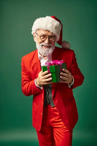 Elegante Santa con barba y sombrero de Navidad celebración presente delante de la cámara, concepto de invierno - foto de stock