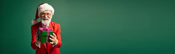 Alegre barbudo Santa com chapéu vermelho e óculos segurando presente verde, conceito de Natal, banner — Fotografia de Stock