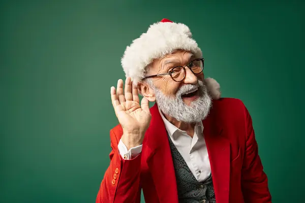 Homem alegre vestido como Papai Noel com chapéu vermelho com mão perto da orelha olhando para a câmera, conceito de inverno — Fotografia de Stock