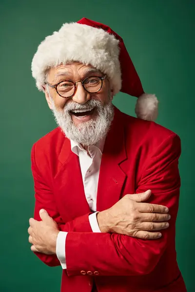 Hombre alegre vestido como Santa posando sobre fondo verde y sonriendo a la cámara, concepto de invierno - foto de stock