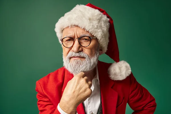 Serious man dressed as Santa looking straight at camera with hand under chin, winter concept — Stock Photo