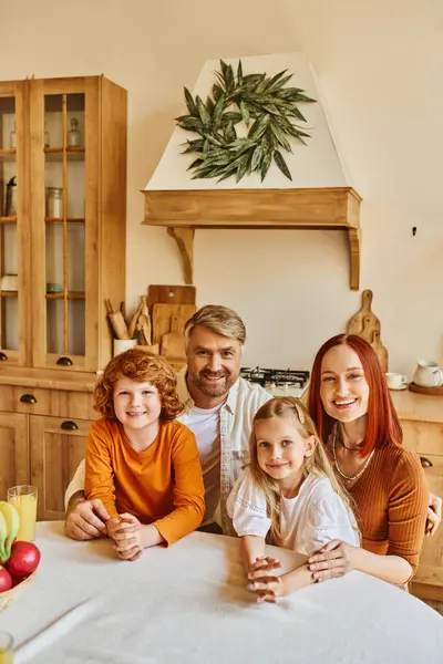 Pais sorridentes com filho e filha olhando para a câmera na cozinha, retrato de família feliz em casa — Fotografia de Stock