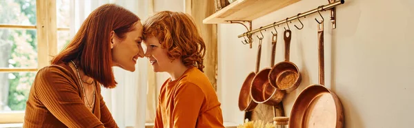 Vista lateral da mãe despreocupada e filho sorrindo cara a cara perto de utensílios de cozinha na cozinha, banner — Fotografia de Stock