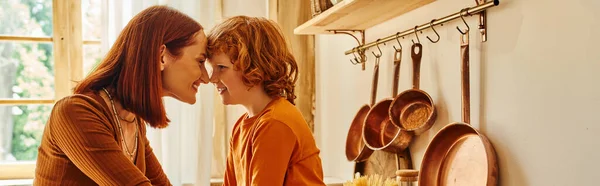 Side view of carefree mother and son smiling face to face near cooking utensils in kitchen, banner — Stock Photo